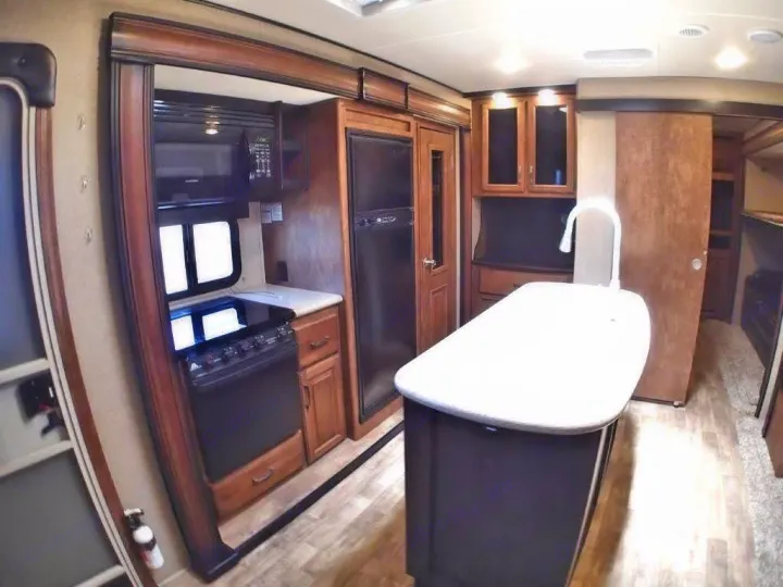 Inside an RV rental kitchen: full amenities including an island sink, stove, microwave, and refrigerator for comfortable trips.. Grand Design Reflection 2016