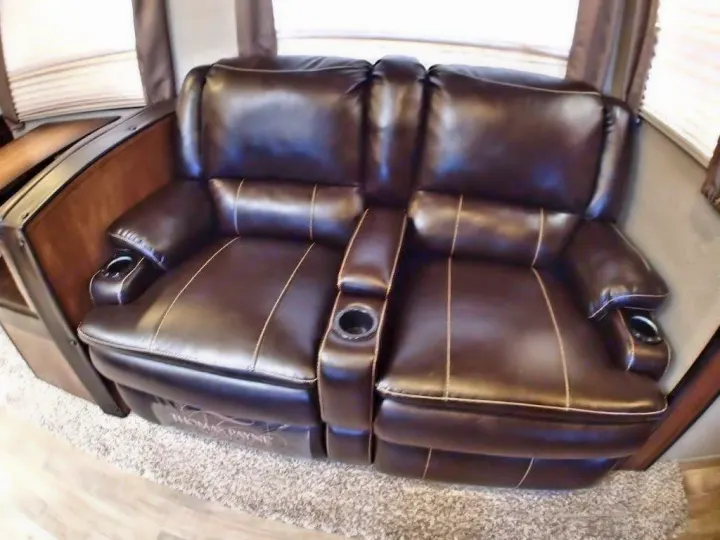 Cozy dark brown leather recliner loveseat with cup holders & white stitching, great for an RV rental. Enjoy RV interior comfort.. Grand Design Reflection 2016