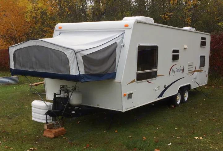 Jay Feather hybrid travel trailer, an ideal RV rental option parked on grass with autumn trees, perfect for camping trips.. Jayco Other 2004