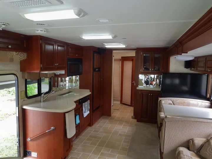 Spacious RV rental interior featuring a full kitchen, dining area, and cozy living space with rich wood cabinetry.. THOR Four Winds Infinity 2005