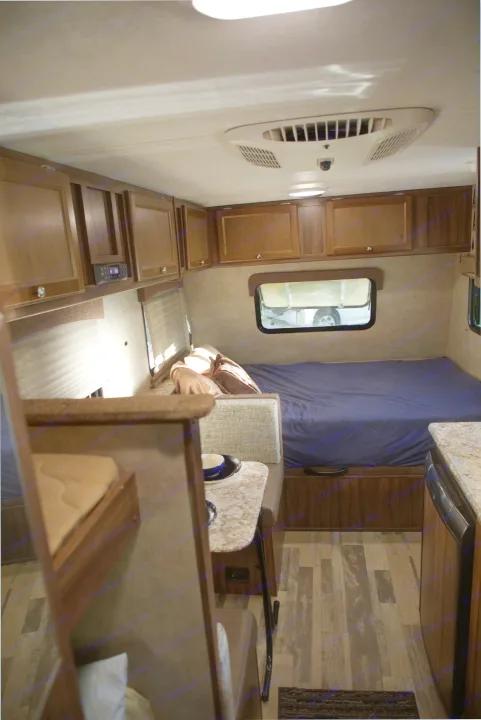 A cozy RV rental interior shows a blue-sheeted bed, dinette, and wood-toned cabinets, offering comfort on the go.. Forest River Other 2018