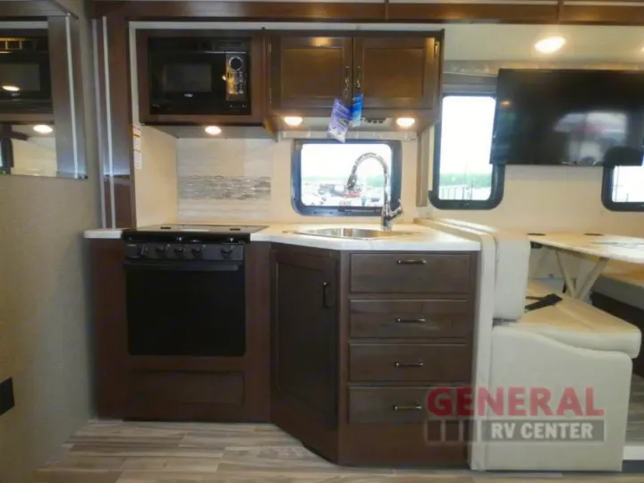 Compact RV rental kitchen and dining area. Features a microwave, stove, sink, cabinets, and dinette with TV for travelers.. Other A.C.E 2020