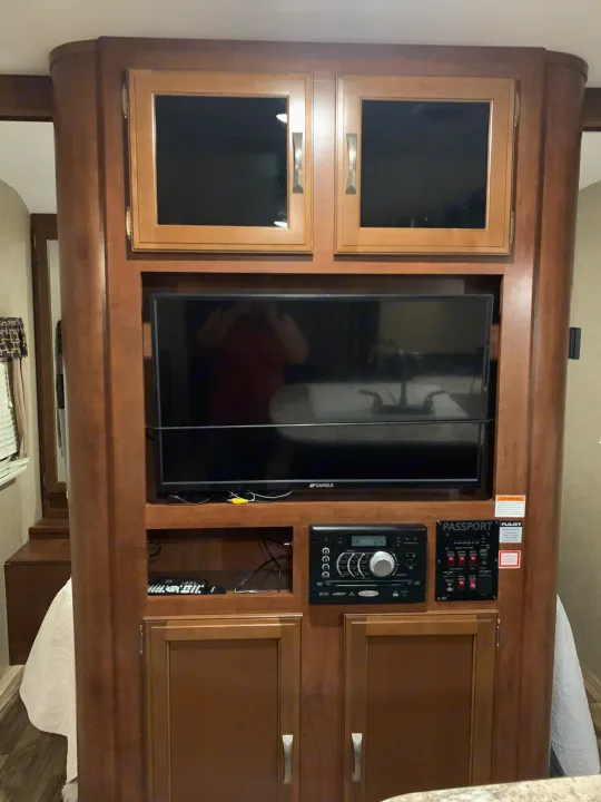 RV rental: Wooden entertainment center with TV, stereo, and RV control panel. Includes storage cabinets for your travels.. Keystone RV Passport Elite 2017