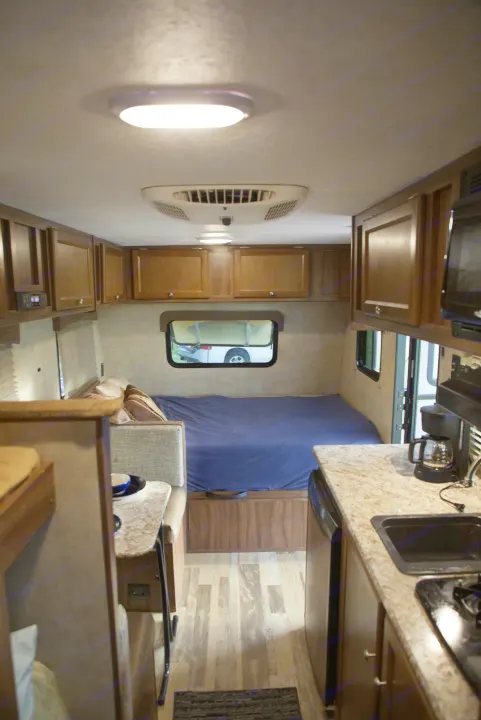 Inside an RV rental: a compact living space with a bed, kitchenette, overhead cabinets, and wood-look flooring.. Forest River Other 2018