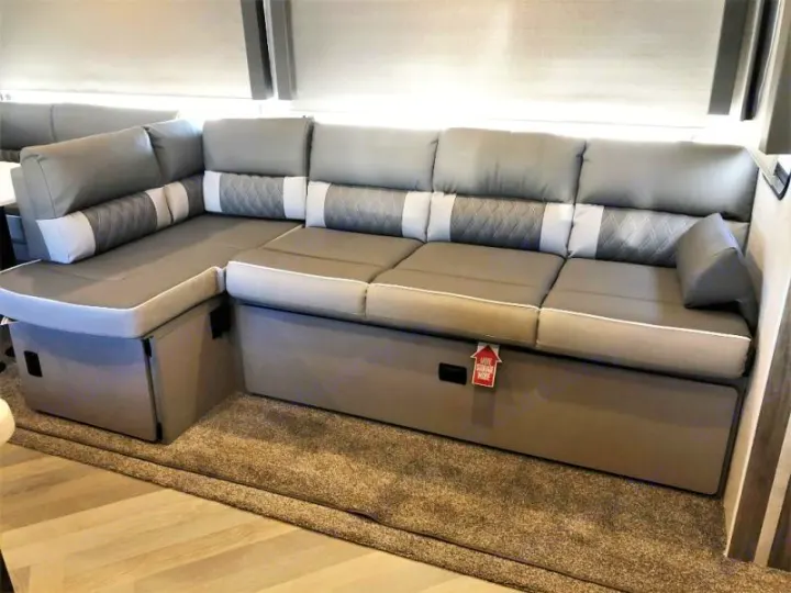 Spacious L-shaped RV sofa with modern gray cushions and pull-out storage, ideal for comfort in an RV rental.. Forest River Salem 2021