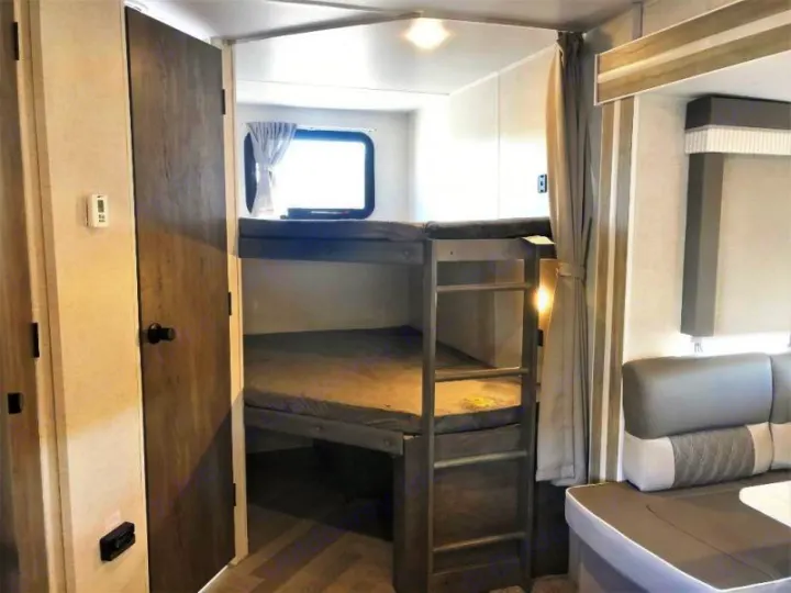 Interior view of an RV rental showing cozy bunk beds, complete with mattresses and a window, ideal for family travel.. Forest River Salem 2021