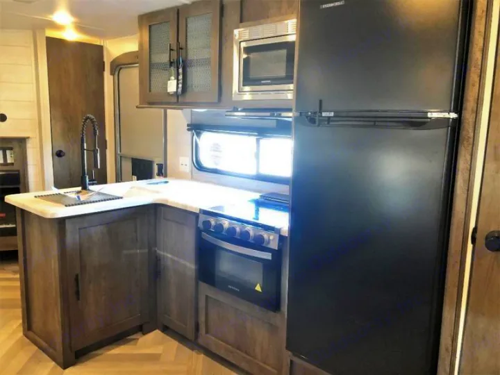 RV rental kitchen: modern design with sink, stove, microwave, and full-size fridge. Ideal for comfortable travels.. Forest River Salem 2021