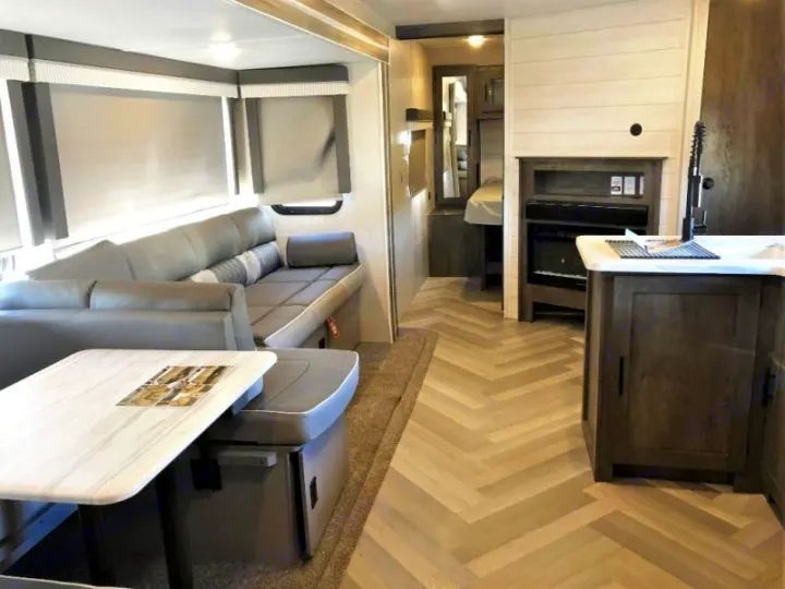 Modern RV rental interior: spacious living area with dinette & sofa, kitchenette, fireplace, and rear sleeping area, light flooring.. Forest River Salem 2021