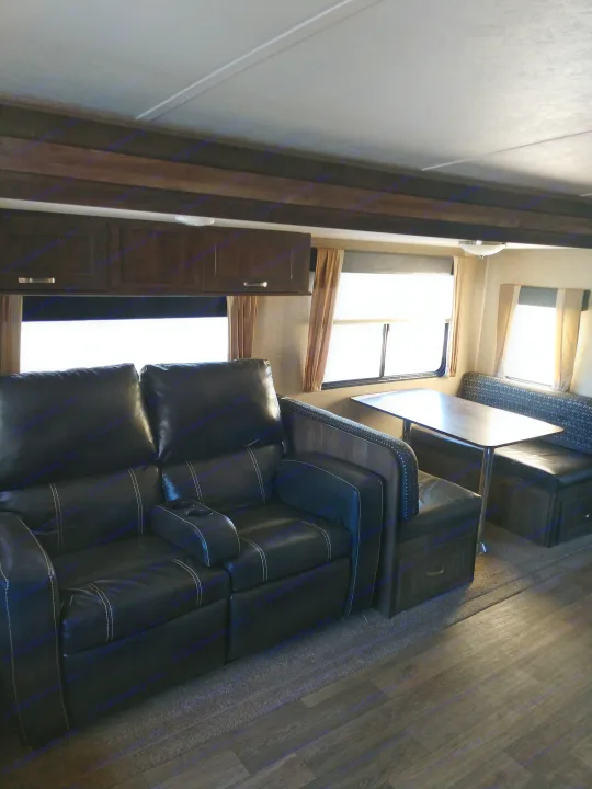 RV rental interior: a comfy living space with black leather recliners, a dining booth, and bright windows.. Forest River Vibe 2018