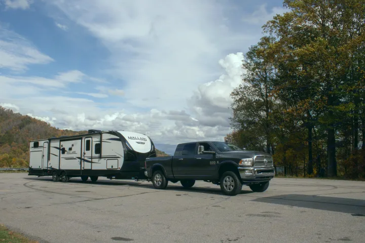 Explore the autumn outdoors! A truck towing a Mallard travel trailer, ideal for an RV rental mountain getaway.. Heartland M-33 2021