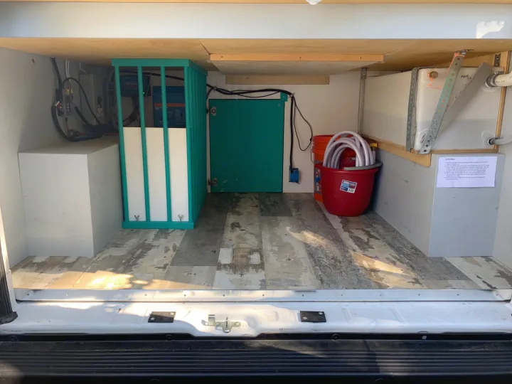 RV rental van's rear utility area, showcasing power system, water tank, storage, and hoses for off-grid adventures.. Dodge 2500 Promaster 2019