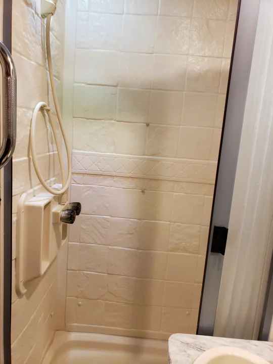 Compact, white shower stall in an rv rental, featuring a handheld shower, functional controls, and built-in caddy for convenience.. Coachmen Other 2018