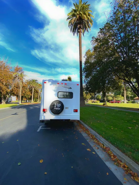 Majestic RV rental parked on a tree-lined street with palm trees, ready for adventure.. Thor Motor Coach Four Winds Majestic 2017