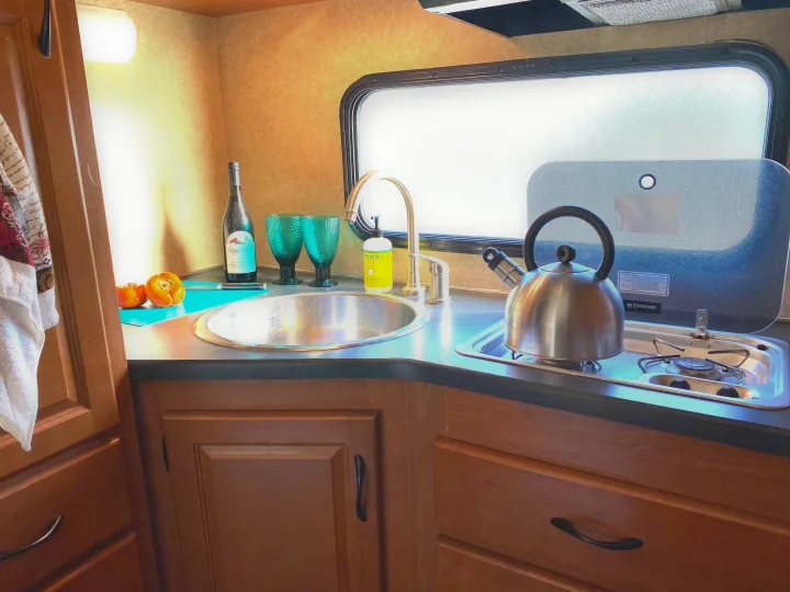 This rv rental features a well-equipped compact kitchen with a sink, stove, and kettle, ready for your road trip meals.. Thor Motor Coach Four Winds Majestic 2017