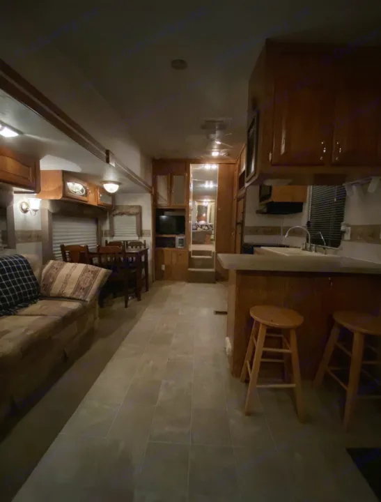Cozy RV rental interior featuring living, dining, & kitchen areas with wood accents and tiled floor. Perfect for travel.. Forest River Other 2012