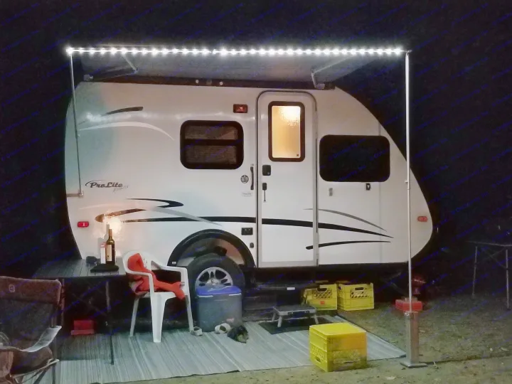 A cozy rv rental at night, illuminated by bright LED awning lights over an outdoor setup with chairs, a table, and gear.. Prolite Prolite Trailer 2015