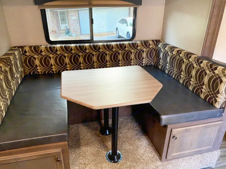 Inside an RV rental: U-shaped dinette with patterned cushions, light wood table, and under-bench storage for comfort.. Other Sun-Lite 2019