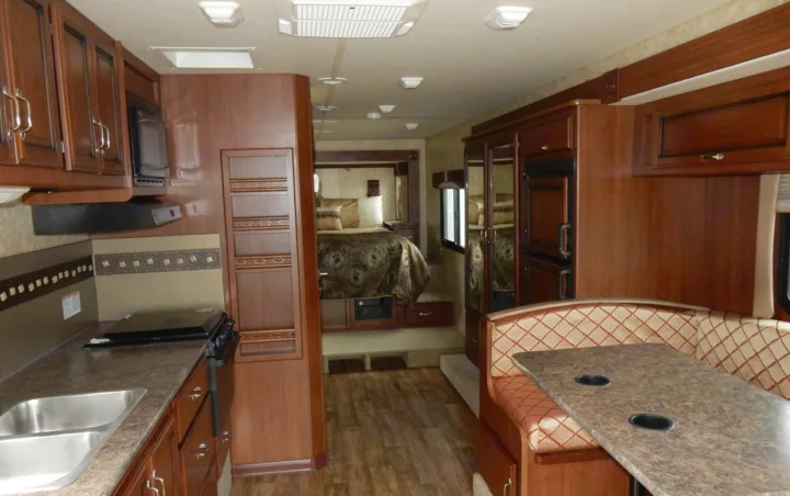 Spacious RV rental interior featuring a full kitchen, comfortable dinette, and rear bedroom.. Fleetwood Storm 2013
