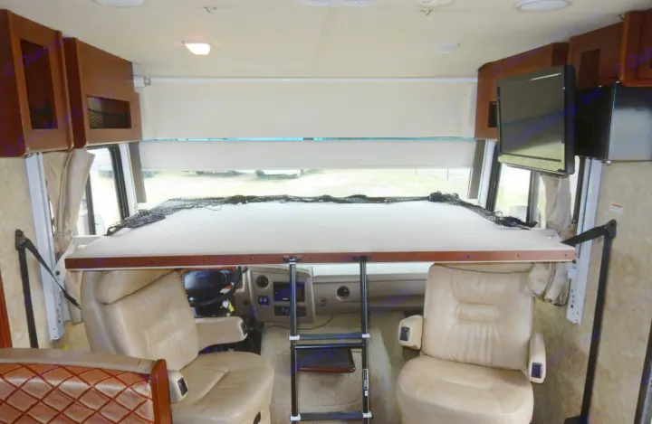 RV rental interior: Overhead bunk bed with safety netting, ladder, and leather driver/passenger seats.. Fleetwood Storm 2013