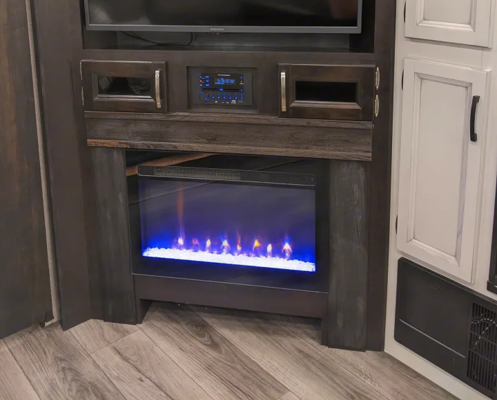 Enjoy the RV rental's cozy media center, featuring a modern electric fireplace, TV, and built-in audio system.. Jayco White Hawk 2021
