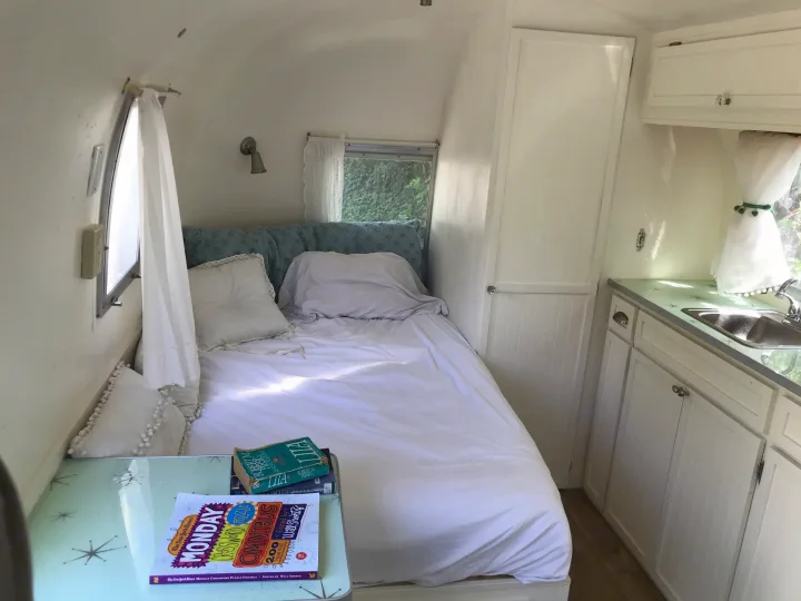 Cozy RV rental interior: a comfortable bed, compact kitchen with vintage green countertop, and storage in this travel trailer.. Airstream Caravel 1968