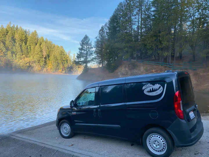 A dark blue Ram ProMaster City camper van on a misty lake boat ramp, perfect for your next RV rental adventure.. Dodge Ram Promaster City 2016