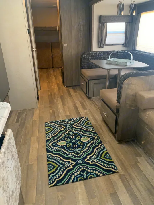 Inside this RV rental, discover a comfy dinette with storage, modern flooring, and bunk beds in the back.. Forest River Vibe 2021