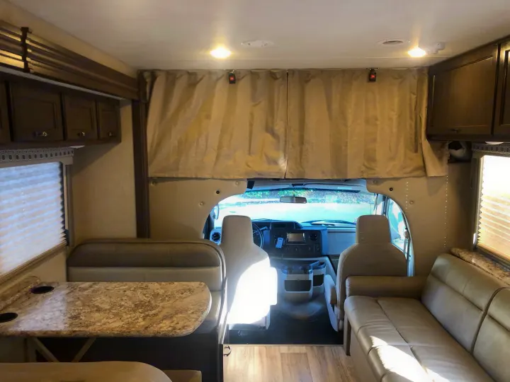 Welcoming rv rental interior features a dinette, sofa, and front cockpit area, ideal for travel.. Thor Four Winds 2020