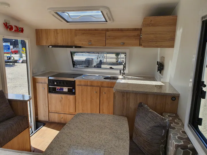 Bright rv rental interior features a kitchen with stove, sink, wooden cabinets, and a dining area.. Avan Aspire 402 2018