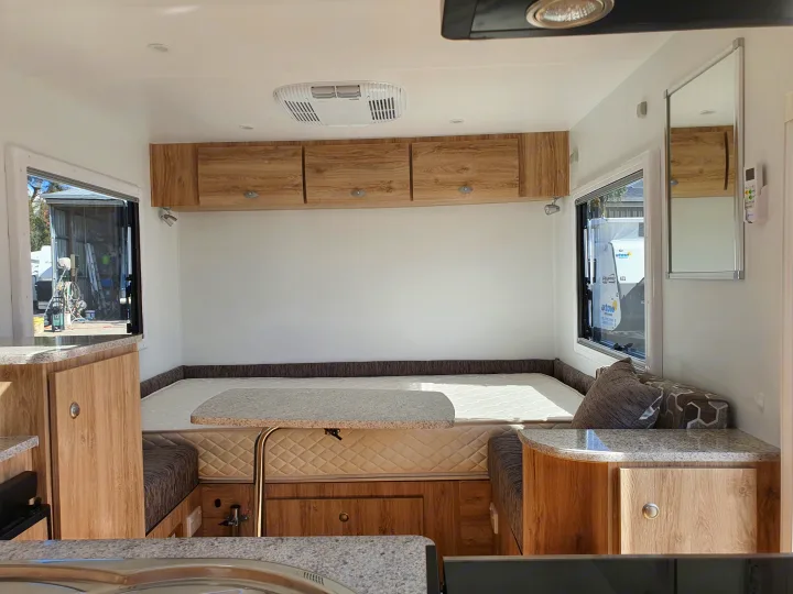 Modern **RV rental** interior showcasing a spacious bed/dinette, wooden overhead cabinets, and a functional kitchen counter.. Avan Aspire 402 2018