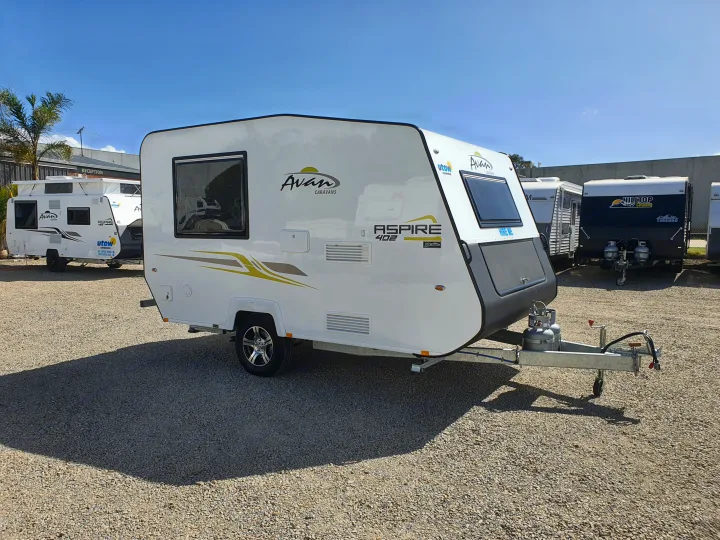 This white Avan caravan, marked "HIRE ME," is ready for rv rental at a dealership display alongside other RVs.. Avan Aspire 402 2018