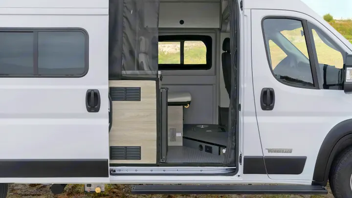 White Winnebago camper van for rv rental, shown with its side door open, offering a view of both the exterior and interior.. Winnebago Winnebago 2021