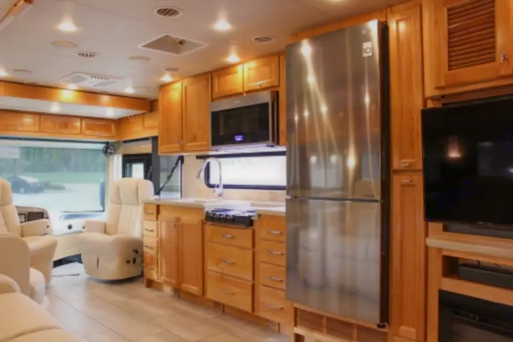 RV rental features: bright interior with modern kitchen (fridge, microwave, stove), cozy chairs, and large TV.. Tiffin Motorhomes Allegro Red 2021