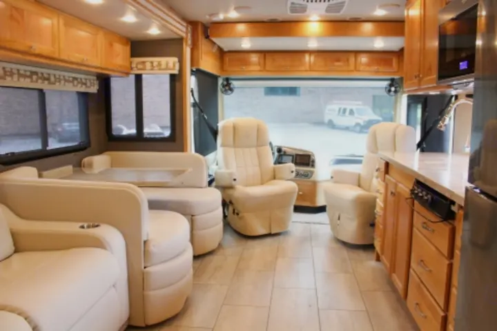 Spacious RV rental interior with cream leather seating, kitchen, and wood cabinets. Ideal for comfortable travel.. Tiffin Motorhomes Allegro Red 2021
