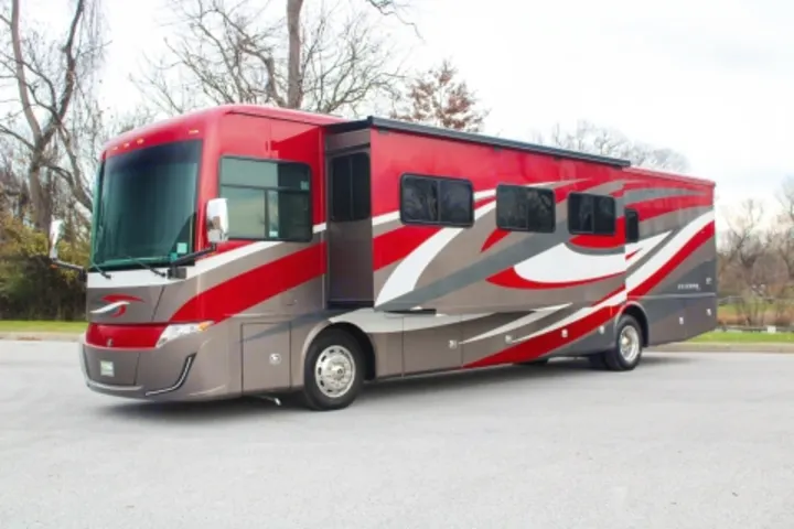 This sleek red, grey, and white motorhome, an ideal RV rental, is parked outdoors with its slide-outs extended.. Tiffin Motorhomes Allegro Red 2021