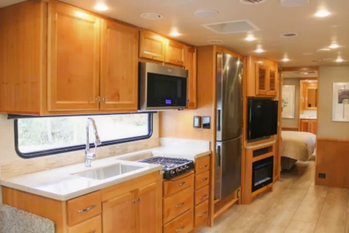 Spacious RV rental interior with bright kitchen, living area, and bedroom visible. Modern appliances & lighting.. Tiffin Motorhomes Allegro Red 2021
