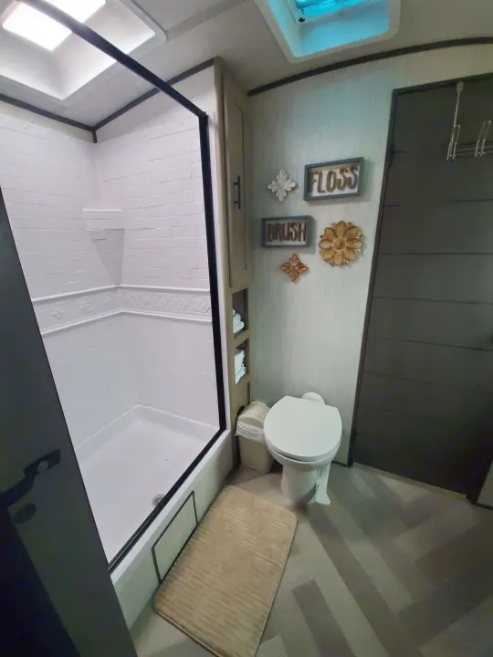 Clean RV rental bathroom features a toilet, shower stall, vanity with storage, and playful FLOSS/BRUSH wall art.. Cruiser Rv Corp Cruiser 2021