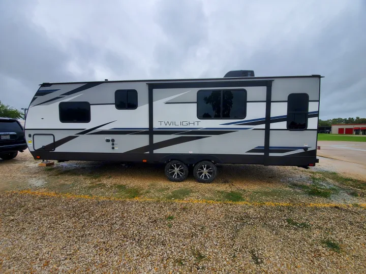 Sleek gray Twilight travel trailer RV rental parked on gravel lot. View of side with windows and wheels.. Cruiser Rv Corp Cruiser 2021