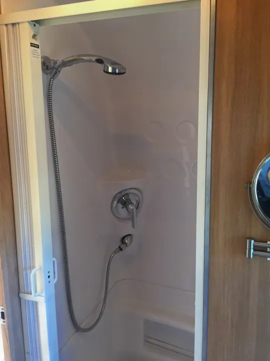 Inside a compact RV rental shower: white base, chrome faucet, and handheld sprayer. Perfect for mobile living.. Airstream Safari 2008
