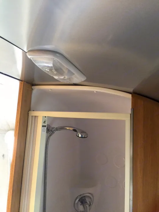 RV rental: Compact bathroom with handheld shower and light fixture. Space-saving design for travel.. Airstream Safari 2008