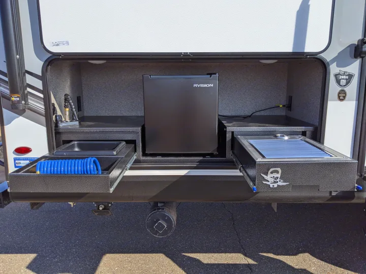 RV rental outdoor kitchen setup. Features a built-in fridge, sink with faucet, and pull-out grill, making camping convenient and fun.. Jayco White Hawk 2021