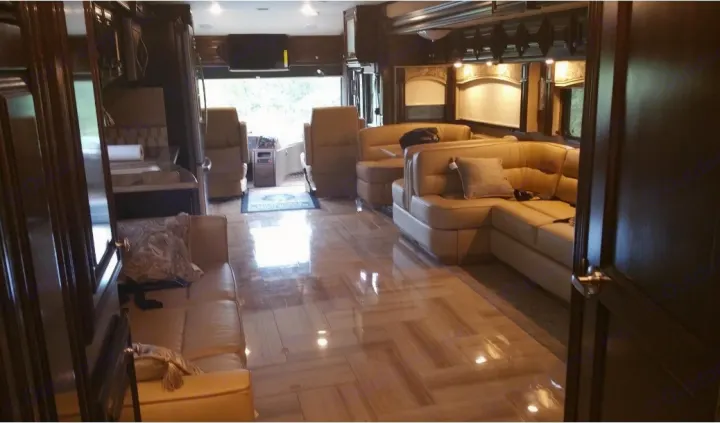 Inside a luxurious RV rental: sleek wooden floors, plush leather seating, and a full kitchen area. Ready for your adventure.. Thor Motor Coach Tuscany 2016