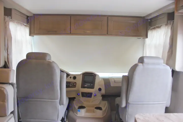 Spacious RV rental cockpit features grey captain's chairs, dashboard controls, overhead cabinets, and a front window blind.. Other Other 2019