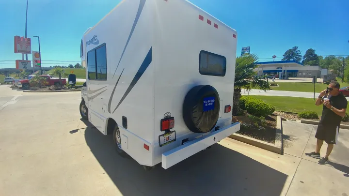 Majestic RV rental at a sunny travel stop, with a man on his phone. Whataburger & Mobil in sight.. Thor 2012 Thor 19G 2012