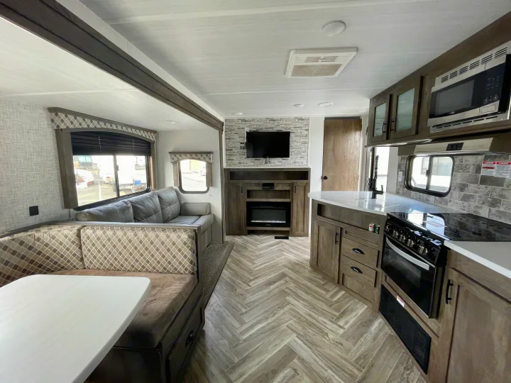 Modern rv rental interior: open living space with sofa, dinette, full kitchen, and entertainment center with fireplace. Stylish and practical.. Forest River Evo T2550 2019