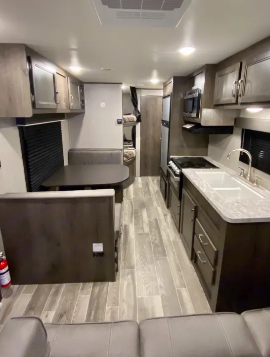 Modern RV rental interior showing a full kitchen, dinette area, and bunk beds, ideal for comfortable travel.. Jayco Jay Flight SLX 2021