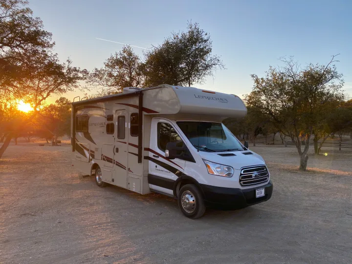 An RV rental, a Coachmen motorhome, parked at sunset in a rustic campsite for travel and camping.. Other Other 2020