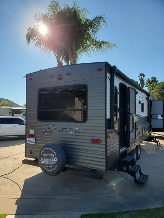 A Zinger RV rental is parked under a sunny sky, steps extended. Your travel trailer for comfortable outdoor adventures.. Crossroads Zinger 2018
