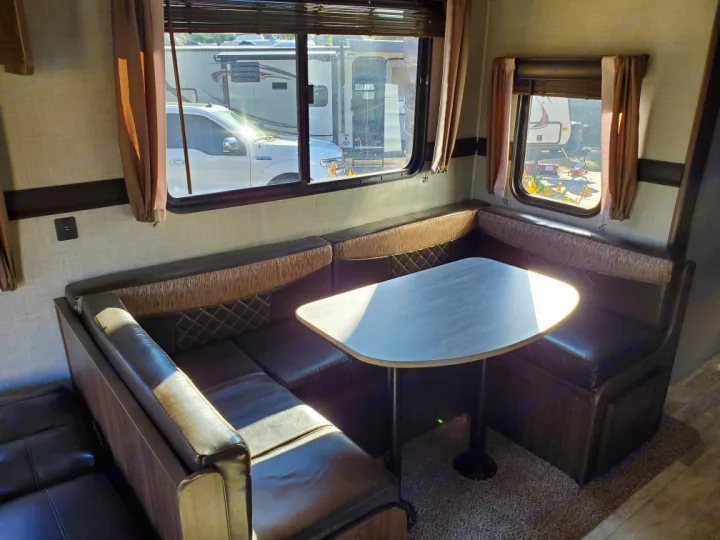 Cozy RV rental dinette featuring a U-shaped booth, table, and large windows. Ideal for comfortable travel and dining.. Crossroads Zinger 2018