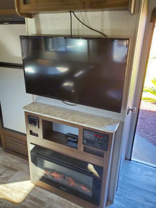 Step inside this RV rental, featuring a flat-screen TV above an electric fireplace and control panels.. Crossroads Zinger 2018